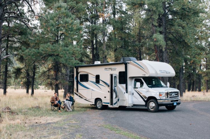 white rv with owners sitting outside
