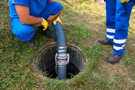 two guys in blue dumping into septic tank